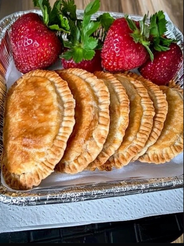 Empanaditas de fresa caseras servidas en un recipiente de aluminio con fresas frescas decorativas